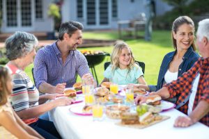 Happy multi-generation family sitting at table in back yard