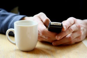 Person with coffee and mobile phone